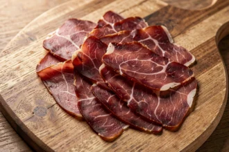 Tranches fines de viande séchée sur une planche en bois